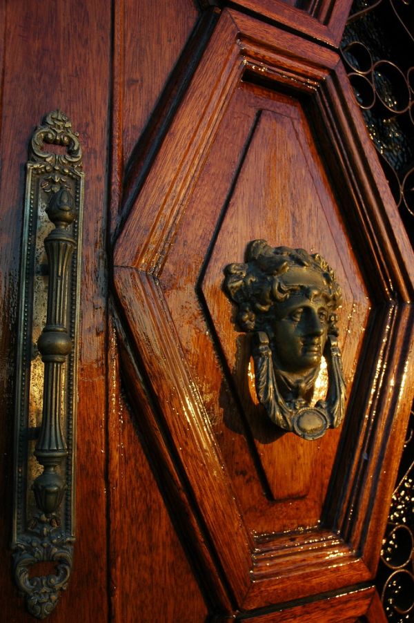 Decorative art nouveau metal handle and door knocker of female face, on laquered door, La Paz, Baja California Sur, Mexico