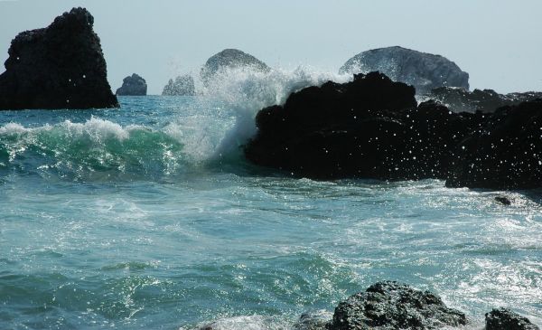 Power of the green wave crashing in, black offshore islands, open blue sky, Pacific coast, South Mazatlan, Mexico