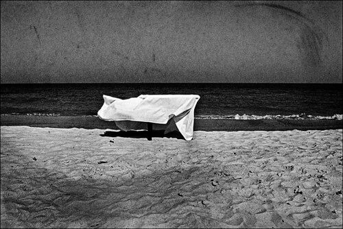 An empty table with a white cloth on a background of black sea